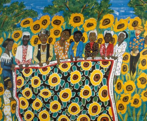 women holding a quilt with sunflowers on it